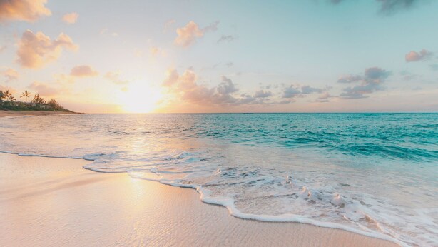 Ein Strand mit sanften Wellen und einem Sonnenuntergang.