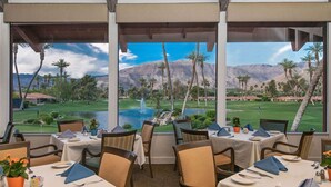 A restaurant with tables set for dining, overlooking a golf course and mountains. - Spectacular view, steps to pool/jacuzzi at Sunrise Country Club-winter available (Rancho Mirage)