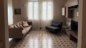 Sala de estar com sofá, poltrona e rack para televisão.