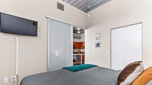 A bedroom with a bed, a TV mounted on the wall, and a closet with a sliding door. - Modern apartment with fitness center (Ann Arbor)