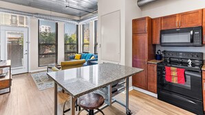 A modern kitchen with a granite countertop, stainless steel appliances, and wooden cabinets. - Modern apartment with fitness center (Ann Arbor)
