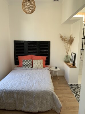 A neatly arranged bedroom with a bed, a small round table, and a shelf with decorative items. - Villa with pool 5 minutes' walk from the beach /A2 (Cavalaire-sur-Mer)