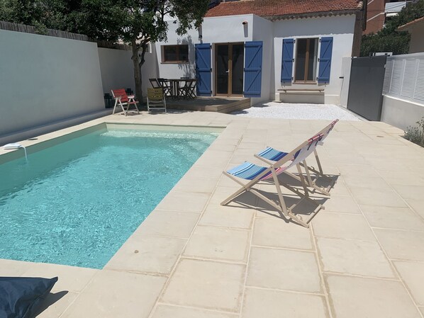 A swimming pool with a tiled deck, a lounge chair, and a table with chairs. - Villa with pool 5 minutes' walk from the beach /A2 (Cavalaire-sur-Mer)