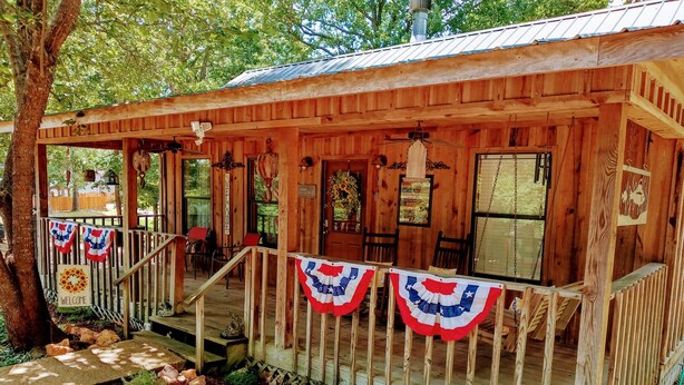 Eine Holzhütte mit Veranda, einem freundlichen Willkommensschild und amerikanischen Flaggen-Dekorationen.