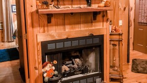 Ein Holzinterieur mit Kamin, einem darüber montierten Fernseher und einem kleinen Tisch mit Dekoration.