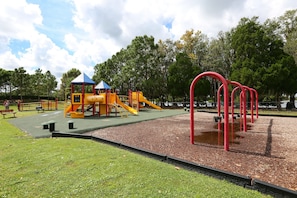 Explore the playground area with a slide and climbing elements, surrounded by benches and a paved walkway.