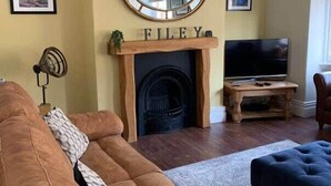 A living room with a fireplace, a television, and a sofa. - Howick House - Gorgeous Cosy Filey Cottage style central location - Sleeps 9 (Filey)