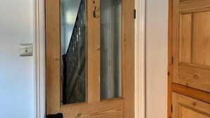 A wooden door with a glass panel, a light switch on the wall, and a wooden cabinet to the right. - Howick House - Gorgeous Cosy Filey Cottage style central location - Sleeps 9 (Filey)