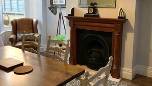 A cozy room with a fireplace, wooden furniture, and a mirror on the wall. - Howick House - Gorgeous Cosy Filey Cottage style central location - Sleeps 9 (Filey)
