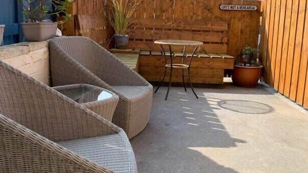 A patio with wicker furniture, a wooden fence, and potted plants. - Howick House - Gorgeous Cosy Filey Cottage style central location - Sleeps 9 (Filey)
