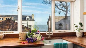 Une cuisine avec vue sur la mer, un évier et une fenêtre donnant sur des immeubles.