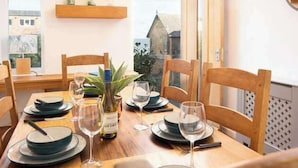 Une table à manger dressée avec des assiettes, des verres et une bouteille, entourée de chaises en bois.