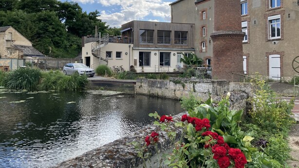 Un canal con un edificio moderno que cuenta con una escalera en espiral y una torre de ladrillo.