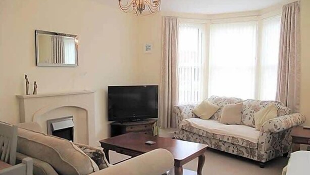 A living room with a sofa, a television, a fireplace, and a chandelier. - Jubilee House  - 4 bedroom central house - bright and spacious, 2 parking space (Filey)