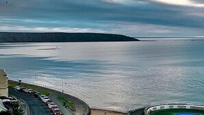 A coastal view with a boat docked near a building with parked cars. - Jubilee House  - 4 bedroom central house - bright and spacious, 2 parking space (Filey)