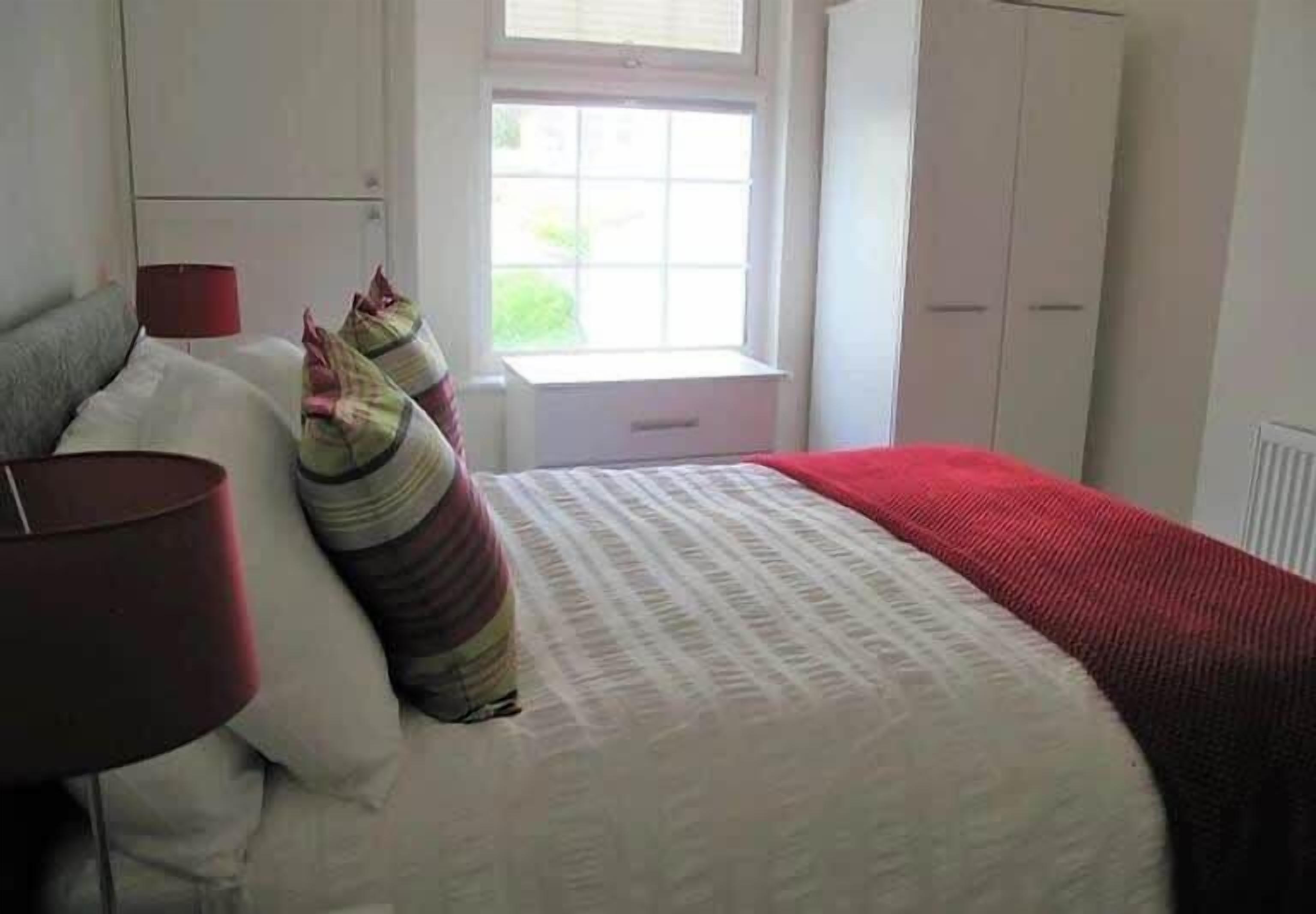 Une chambre à coucher avec un lit, des oreillers, une fenêtre et une armoire.