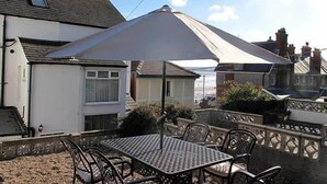 Un espace patio aménagé avec une table et des chaises, un grand parasol et une vue sur les maisons voisines.