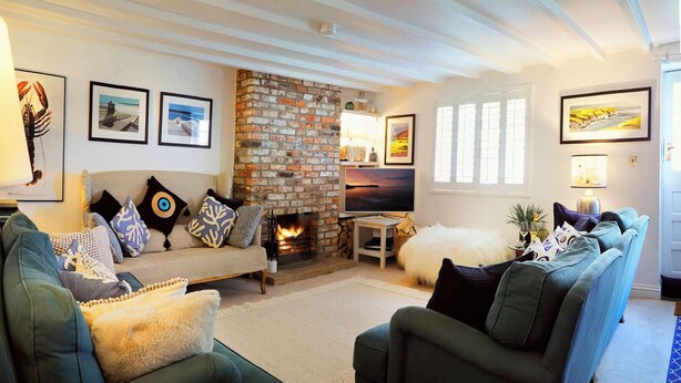 A cozy living room with a fireplace, a sofa set, and framed artwork on the walls. - Flora Dora - Luxury cottage, central, beautiful (Filey)