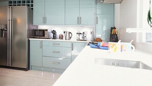 A modern kitchen with light blue cabinets, stainless steel appliances, and a white countertop. - Flora Dora - Luxury cottage, central, beautiful (Filey)