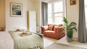 A bedroom with a bed, a sofa, a cabinet, and a window with curtains. - Glenview House - Fantastic child friendly house - rear garden - parking (Filey)