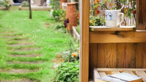A wooden shelf with a white mug and a book, set against a garden backdrop. - Glenview House - Fantastic child friendly house - rear garden - parking (Filey)
