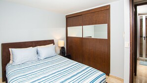 Une chambre à coucher comprenant un lit, une table de chevet, une armoire en bois et un miroir.