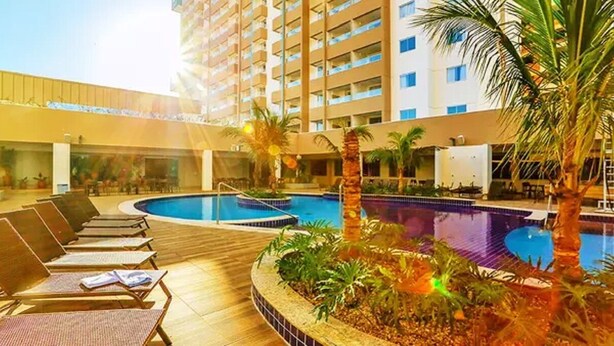 A hotel pool area with sun loungers and palm trees. - Enjoy Olimpia Park Resort (SP)