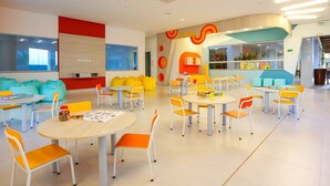 A brightly colored children's play area with tables and chairs, bean bags, and a kitchen area. - Enjoy Olimpia Park Resort (SP)
