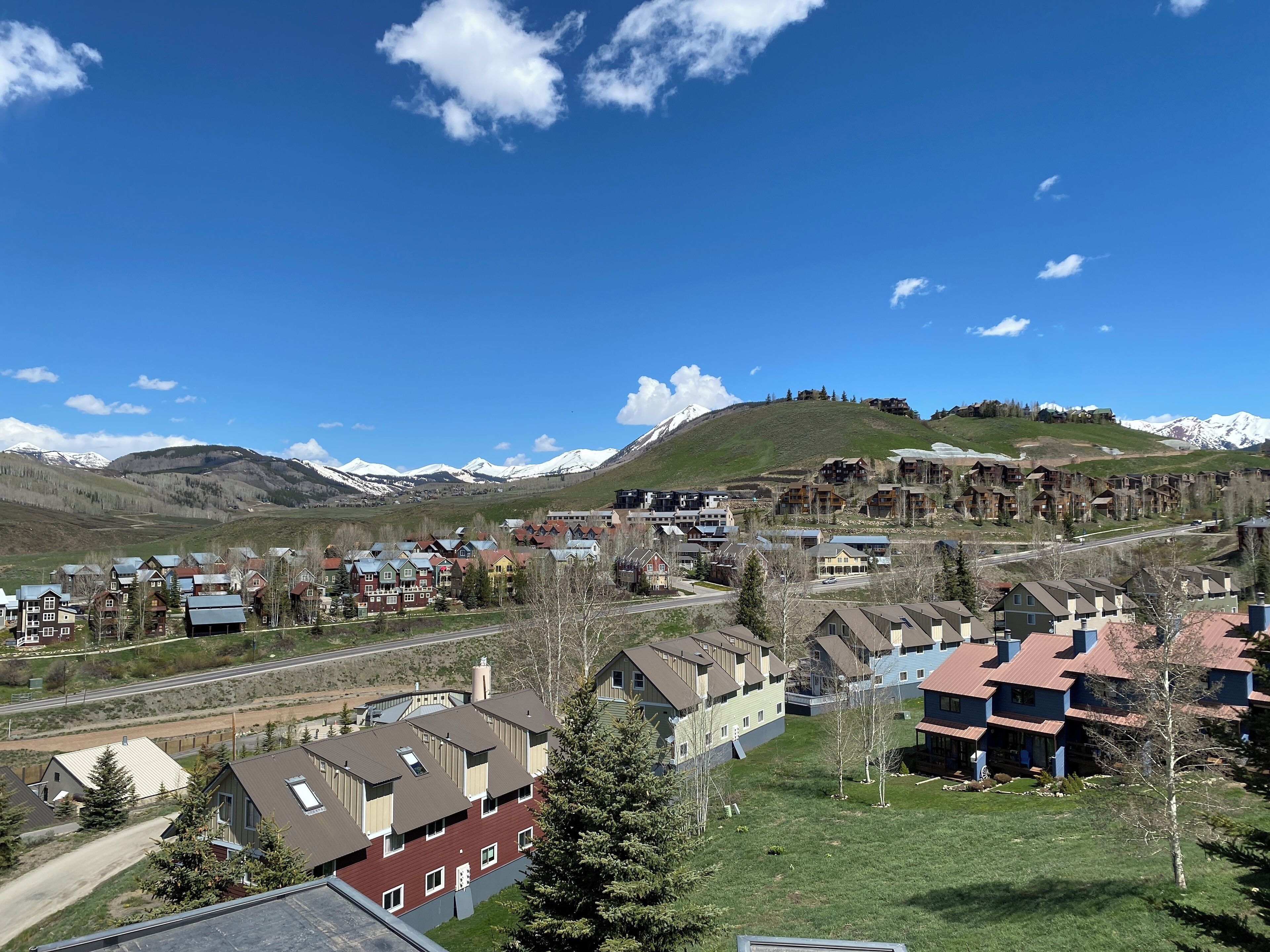 A residential area with houses, a railway track, and mountains in the background.
