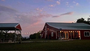 A red barn with a metal roof and a covered area with a red roof. - Presidential Barndominium at the Stable at Bear Mountain (Eureka Springs)