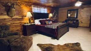 A log cabin interior with a bed, a sofa, a rug, and a mounted animal head. - Presidential Barndominium at the Stable at Bear Mountain (Eureka Springs)