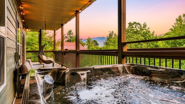 Un bain à remous avec une terrasse en bois et une vue sur les montagnes.