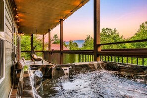 Un jacuzzi con muelle de madera y vista a las montañas.