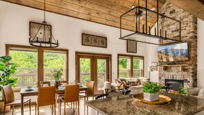 Une cuisine spacieuse dotée d’un grand îlot central, d’un plafond en bois et d’une cheminée en pierre.