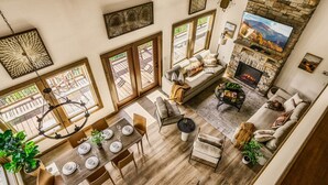 Un vaste espace de vie agrémenté d’une cheminée, d’une table à manger pour quatre personnes et d’un coin salon confortable.