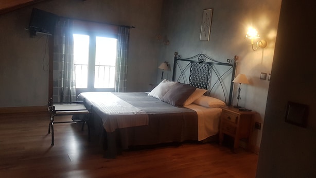 A bedroom with a bed, bedside tables, a lamp, a window with curtains, and a wall-mounted picture. - HTR-40/560 (Sebulcor)