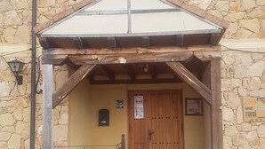 A rustic stone building with a wooden entrance, a tiled porch, and a sign indicating it is a rural hotel. - HTR-40/560 (Sebulcor)