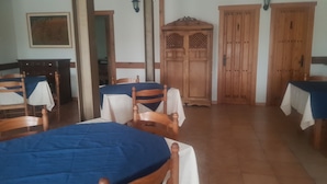 A dining area with wooden tables and chairs, a wooden cabinet, and a door with a figure on it. - HTR-40/560 (Sebulcor)