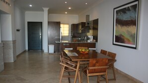 A spacious dining area with a wooden table and chairs, a kitchen in the background, and a framed artwork on the wall. - GATED CONDO 2bd/2bth sleeps 5 Oceanview and Minutes from everything in Cabo! (Cabo San Lucas)