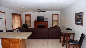 A living room with a fireplace, a television, and a dining area with chairs.