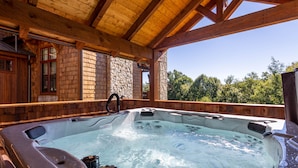 A hot tub in a wooden cabin with stone walls and a clear view of trees. - Birds Nest Retreat - Eagles Nest Village, hot tub, views, outdoor fireplace! (Banner Elk)