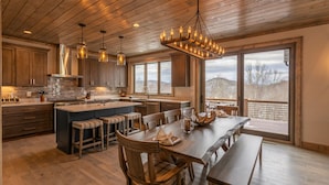 A spacious kitchen with a large island, wooden cabinets, and a view of the outdoors. - Birds Nest Retreat - Eagles Nest Village, hot tub, views, outdoor fireplace! (Banner Elk)