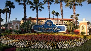 Placa de Westgate Lakes Resort & Spa, rodeada por palmeiras e canteiros de flores coloridas.