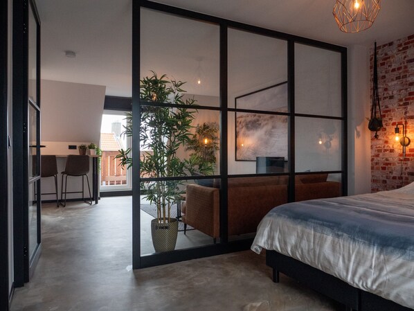 Relax in a spacious bedroom with a large bed, geometric partition, and a cozy seating area.