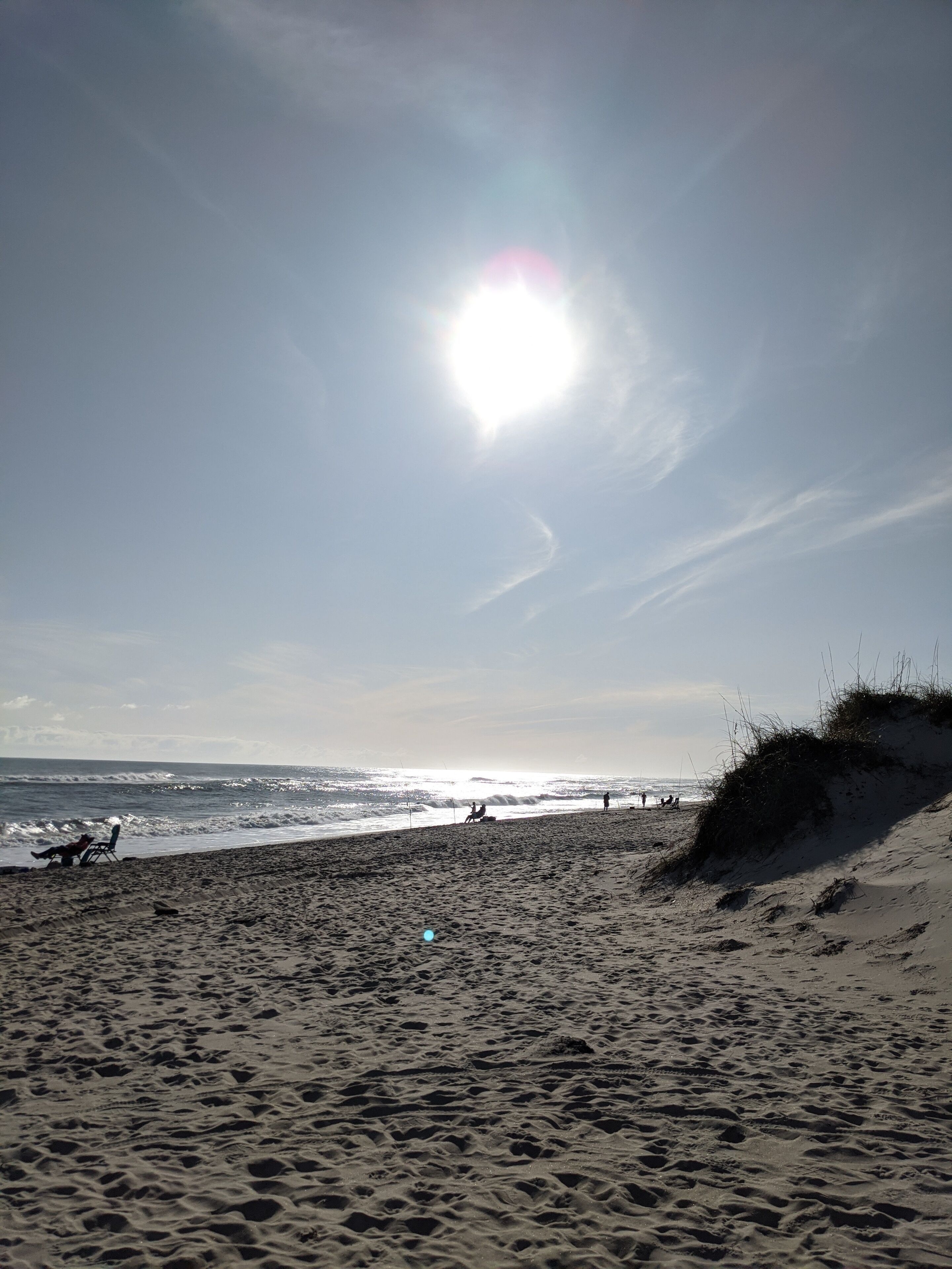 Une plage avec du sable, des vagues et un ciel dégagé.
