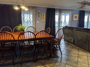 Un coin repas avec une table et des chaises en bois, une plante en pot et une vue par une fenêtre ornée de rideaux.