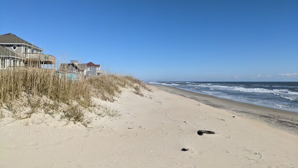 En strand med et hus og klitter.