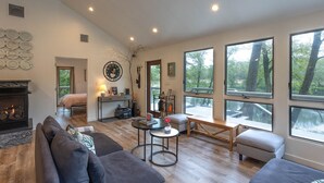 Un salon spacieux doté d’une cheminée, de grandes fenêtres et offrant une vue sur l’extérieur.