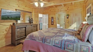 A wooden cabin bedroom with a bed, dresser, and a ceiling fan. - Welcome to Bearfeet Retreat, a pristine cabin in a quiet corner in the heart of Wears Valley. (Sevierville)