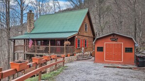 A rustic cabin with a green roof, a stone chimney, and a red door. - Welcome to Bearfeet Retreat, a pristine cabin in a quiet corner in the heart of Wears Valley. (Sevierville)